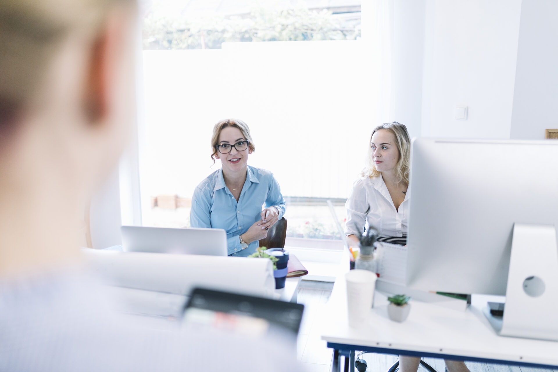 Zwei Frauen sitzen an Ihren Schreibtischen