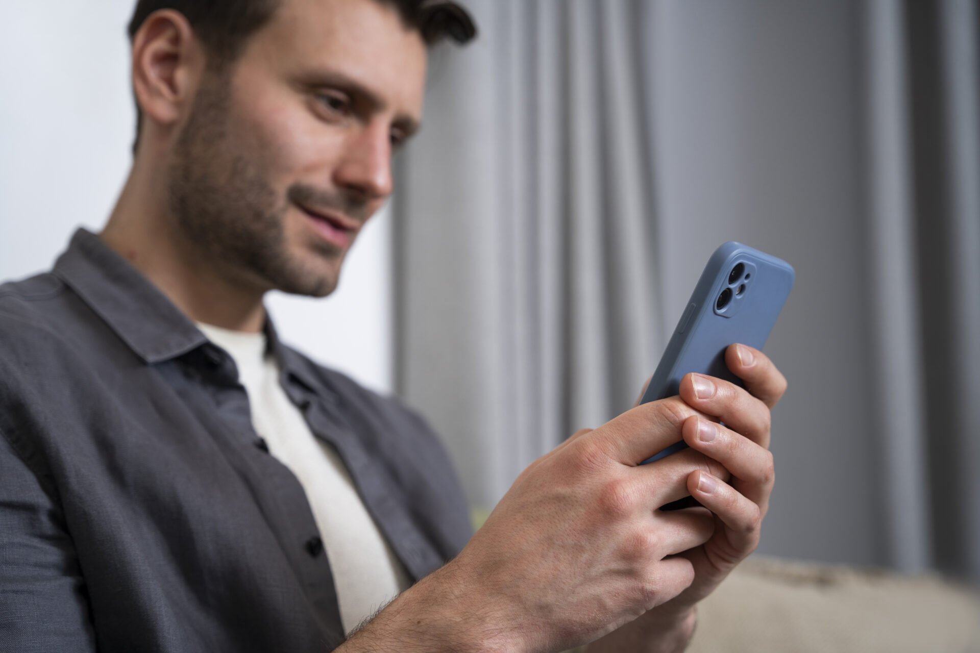 Mann hält Smartphone in der Hand und wirkt zufrieden
